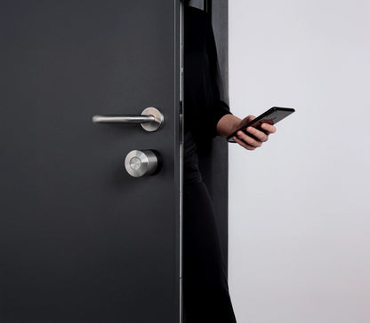 Persona abre la puerta con el Nuki Smart Lock Pro y el smartphone