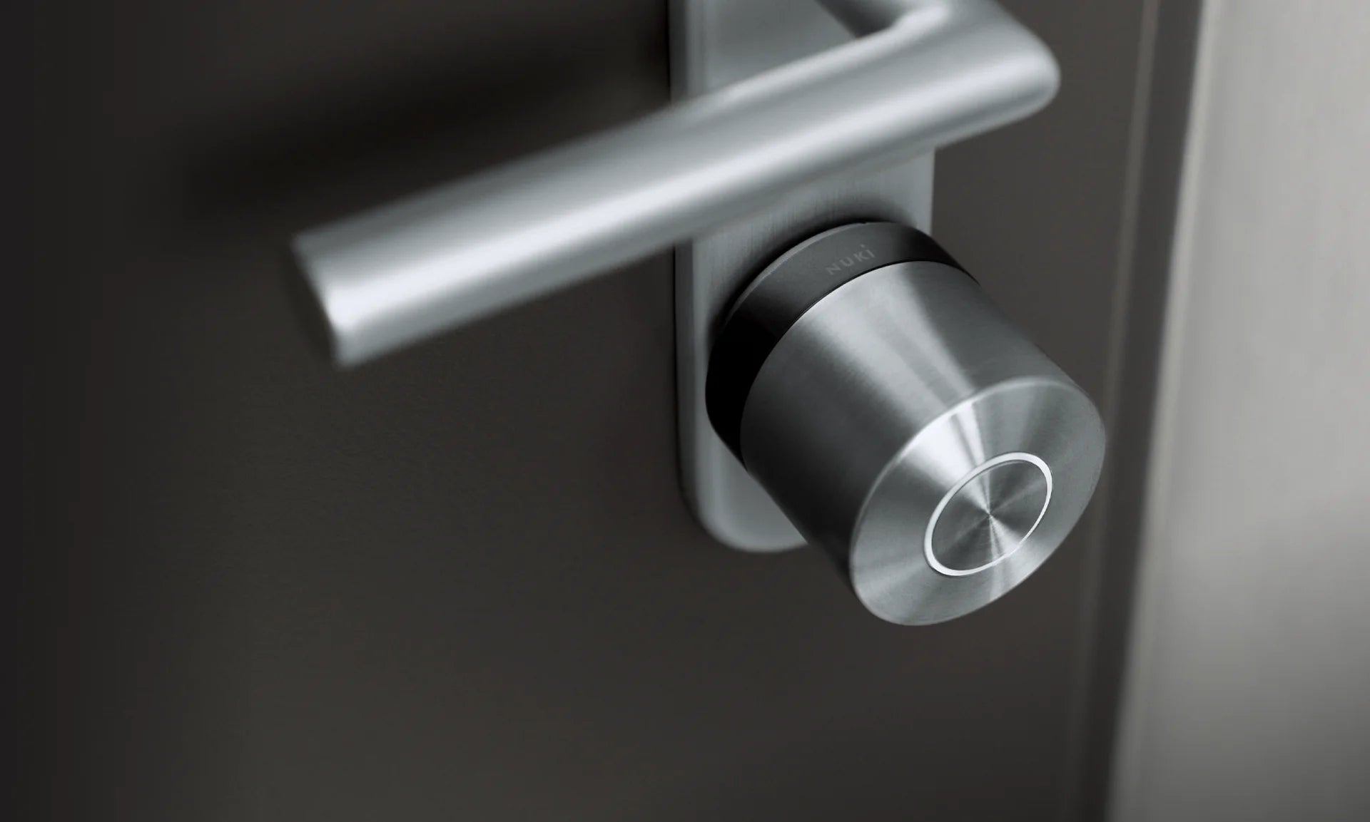 Nuki Smart Lock Ultra plateado instalado en una puerta oscura