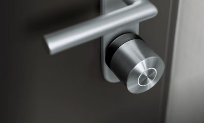 Nuki Smart Lock Ultra plateado instalado en una puerta oscura